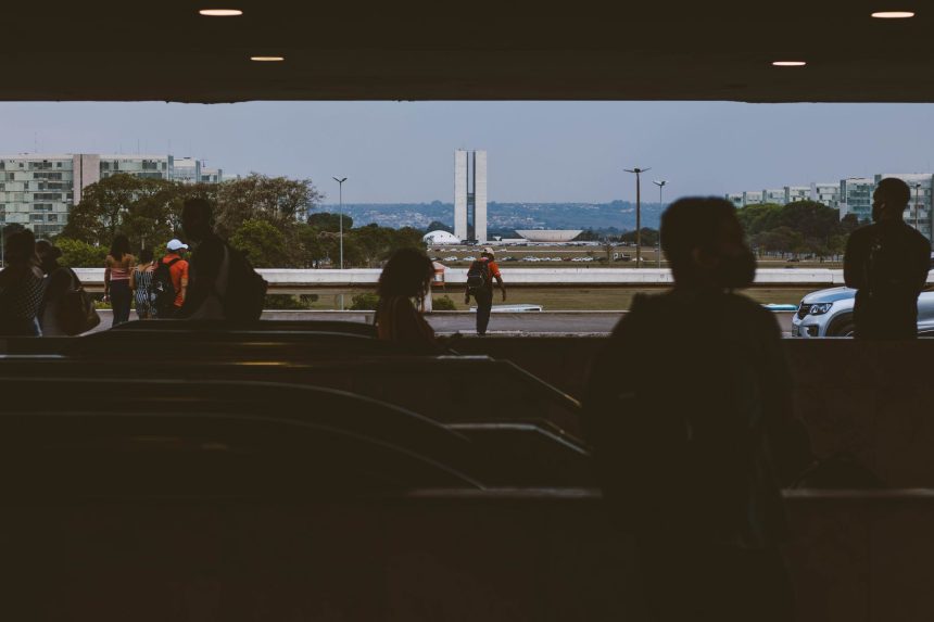 Silhuetas de pessoas em uma passagem subterrânea diante do Congresso Nacional, em Brasília.