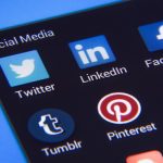 Smartphone cercado por ícones de redes sociais e elementos de comunicação digital.